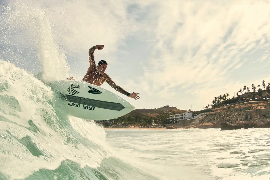 Surfer catching air with the coastline behind