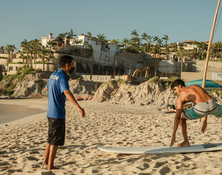 Instructor coaching a student's pop-up on the beach