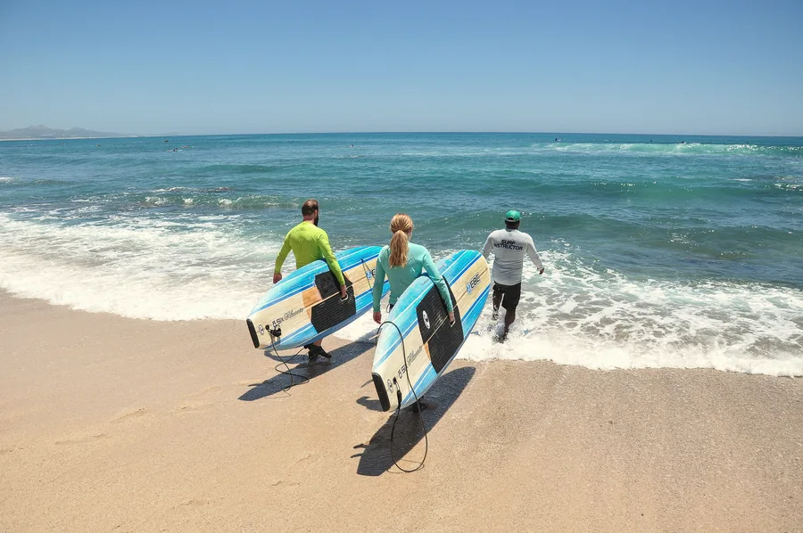 Group heading into the water with SUP boards and an instructor