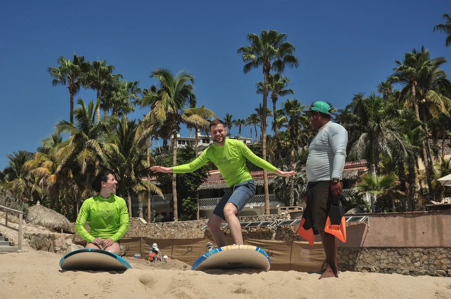 Two students in Mike Doyle Surf School rashguards practicing on the beach