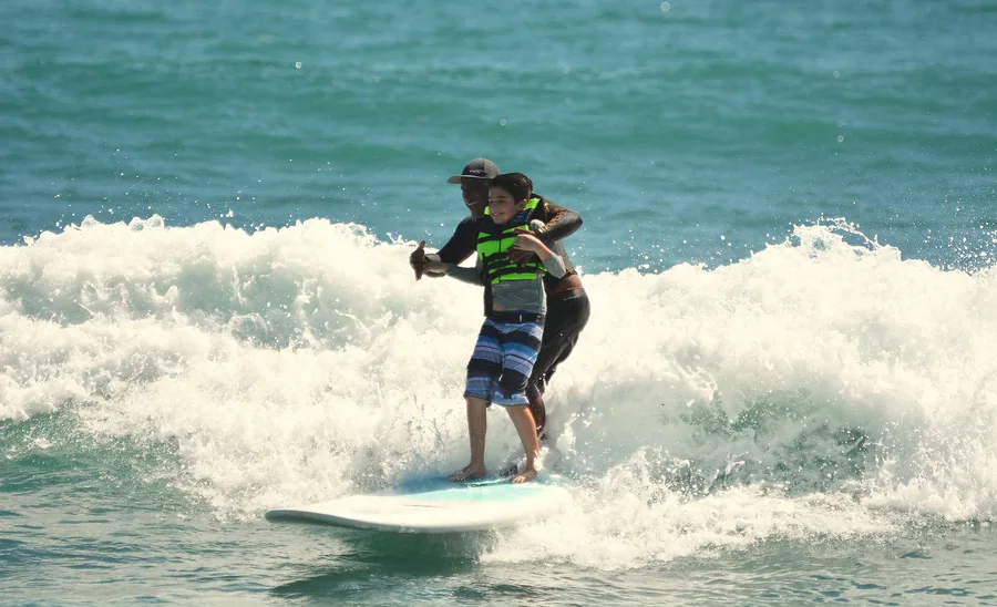 Instructor and child sharing a wave on a paddleboard