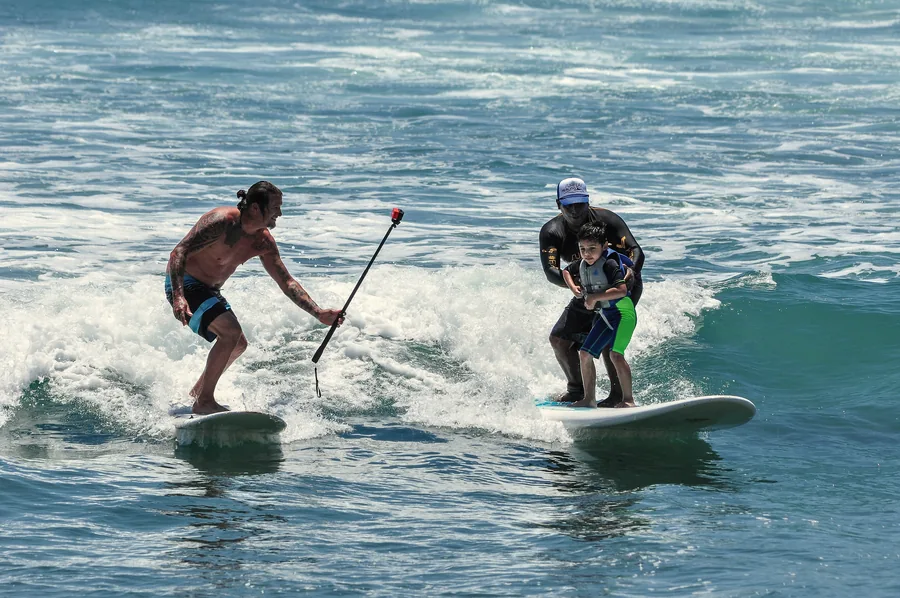 Surfers sharing a wave with a selfie stick